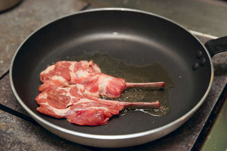 Raw rack of lamb on hot pan on restaurant kitchenの写真素材