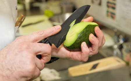 Chef is peeling avocado with sharp japanese knifeの写真素材