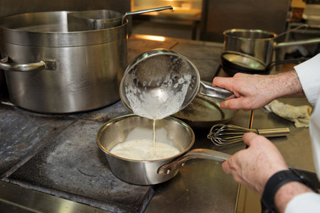 Chef is cooking sauce on electric stove, professional kitchenの写真素材