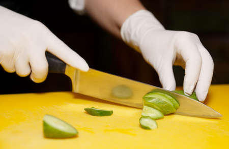Chef is cutting cucumber on yellow plankの写真素材