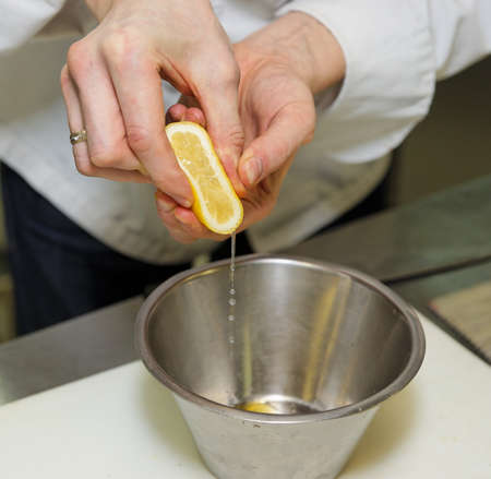 Chef is adding  lemon juice in sauce at restaurant kitchenの写真素材
