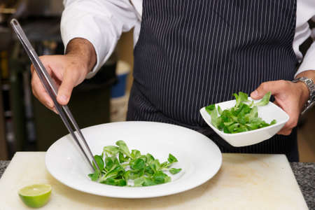 Chef is mixing salad at professional kitchenの写真素材