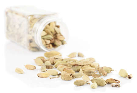 Cardamom spilled from plastic container, isolated on whiteの写真素材