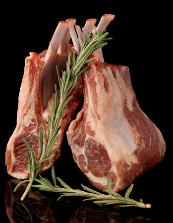 Raw rack of lamb with fresh rosemary isolated on black backgroundの写真素材