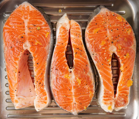 Three marinated salmon steaks prepared for frying on grill pan