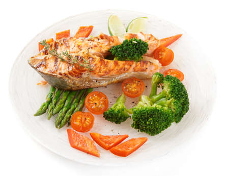 Salmon steak with vegetables in plate isolated on white backgroundの写真素材