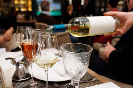 Waiting is pouring white wine in restaurantの写真素材