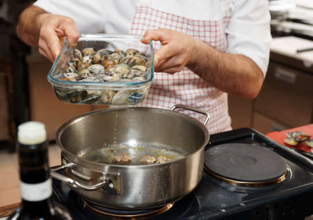 Chef is adding water from where live clams stay to make perfect brothの写真素材