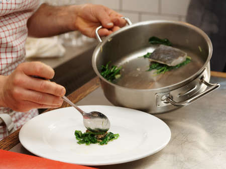 Chef is serving steamed seabass with spinachの写真素材