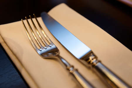 Fork, knife and napkin on restaurant table, warm lightの写真素材