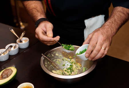 Chef is adding green onion in a dishの写真素材