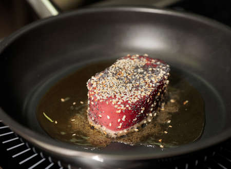 Tuna steak being fried on olive oil on panの写真素材