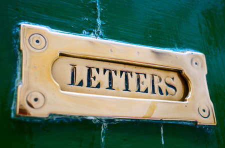 Brass letter box in old painted door, close-upの写真素材