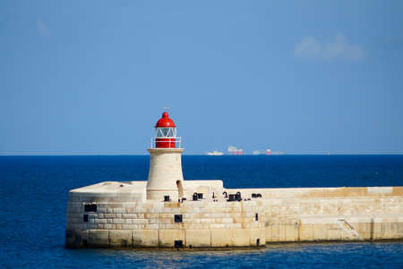 Lighthouse on Malta, Mediterranean sea, cargo ships visible far awayの写真素材