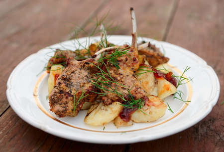Grilled rack of lamb with fried potatoes and onion chutnee on old wooden tableの写真素材
