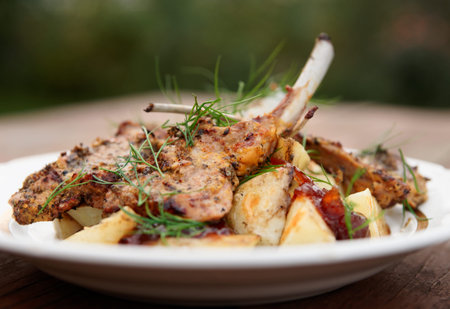 Grilled rack of lamb with fried potatoes and onion chutnee shot outdoorsの写真素材