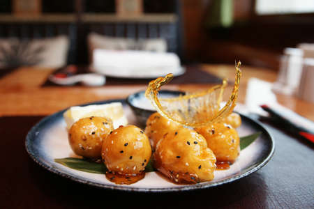 Caramelized fruits in dough, chinese dessert, in plate on restaurant tableの写真素材