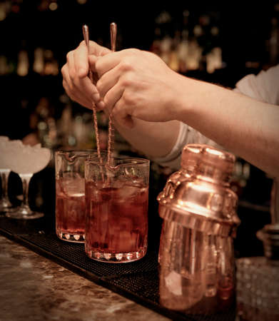 Bartender is stirring cocktails in mixing glassesの写真素材