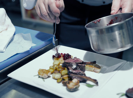Chef is decorating grilled rack of lamb with currant sauce