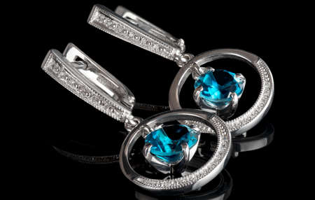 White gold earrings with topazes, isolated on black backgroundの写真素材