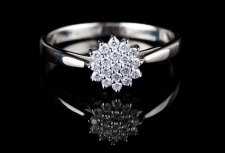 White gold ring with diamonds shot on black surface, macro