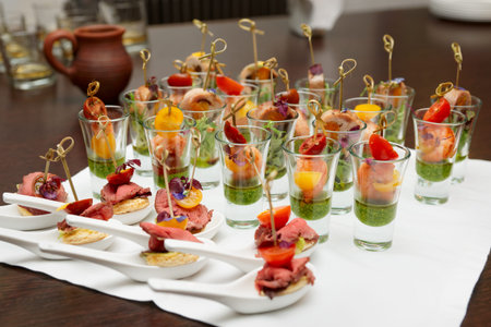 Various meat and seafood snacks in shot glasses on tableの写真素材