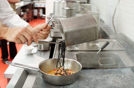 Chef is cooking pasta with seafood at commercial kitchenの写真素材