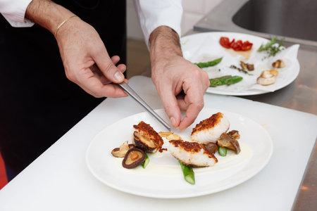 Chef is cooking a fish dish with vegetables and mushrooms