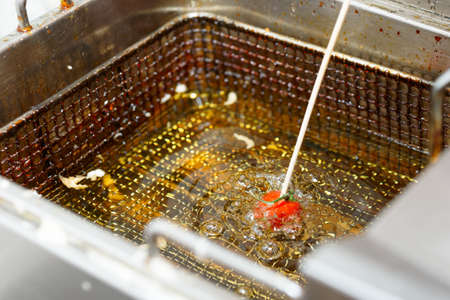 Tomato being fried in oil at professional kitchenの写真素材