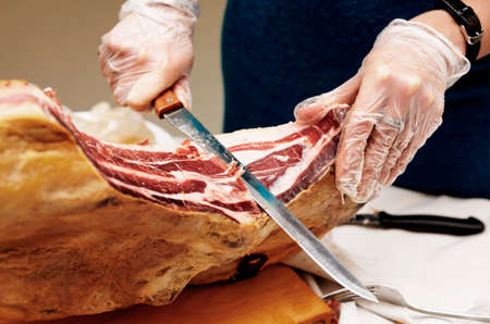 Waiter is slicing jamon (prosciutto) in restaurant, tonedの写真素材