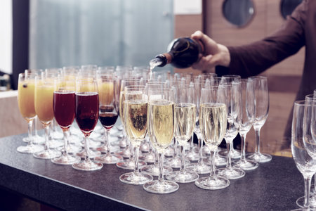 Bartender is pouring sparkling wine in glasses, making cocktails, toned