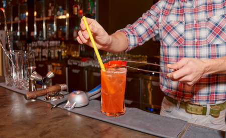 Bartender is decorating cocktail with slice of bell pepper