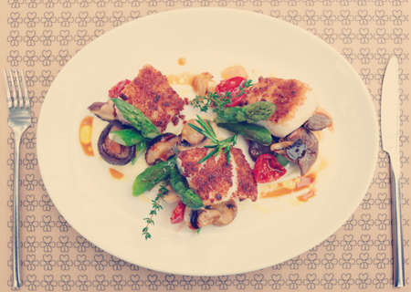 Fish fillet with mushrooms and asparagus on restaurant table, toned imageの写真素材