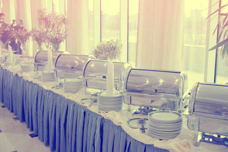 Table with dishware and shiny marmites waiting for guests, toned imageの写真素材