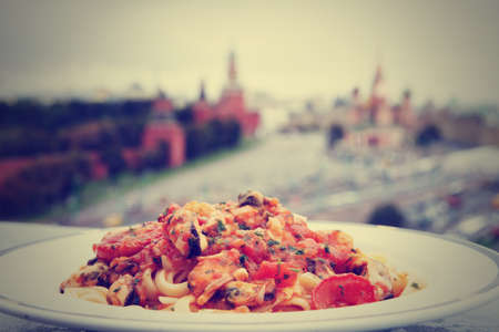 Fried mussels with pasta, Moscow Kremlin in the blurred background, toned imageの写真素材