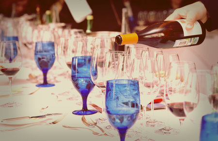 Waiter is pouring wine during a winetasting event, toned image