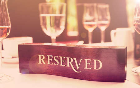 Wooden reserved plate on an arranged restaurant table, toned imageの写真素材