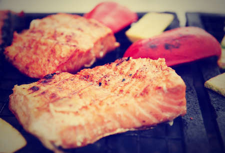 Salmon steaks being fried on grill with vegetables, toned imageの写真素材