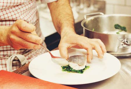 Chef is serving steamed seabass with spinach, toned imageの写真素材