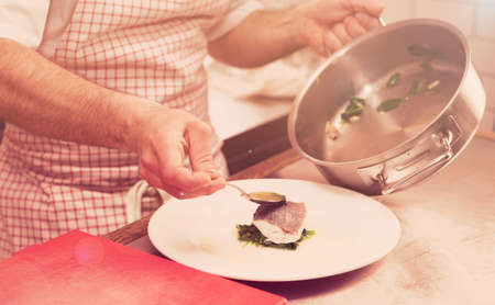 Chef is serving steamed seabass with spinach, toned imageの写真素材