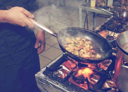 Chef is cooking seafood dish - stir fry method, toned imageの写真素材