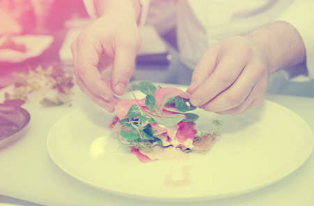 Chef is cooking appetizer on professional kitchen, toned imageの写真素材