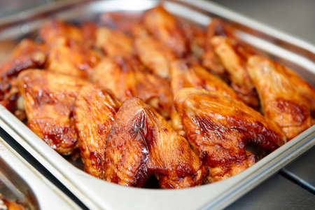 Grilled chicken wings in stainless steel container, commercial kitchenの写真素材