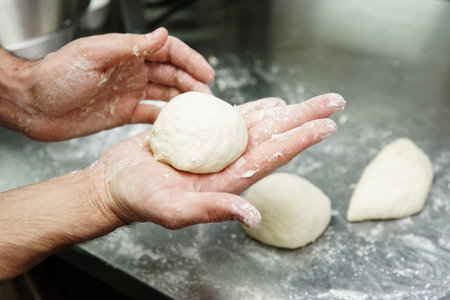 Pizza maker is cooking dough at commercial kitchen