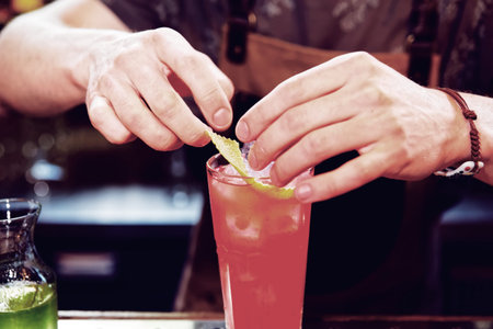 Bartender is adding zest to the cocktail, toned image