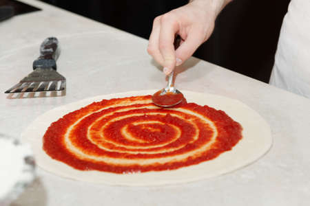 Pizza making in a restaurant, putting tomato sauceの写真素材