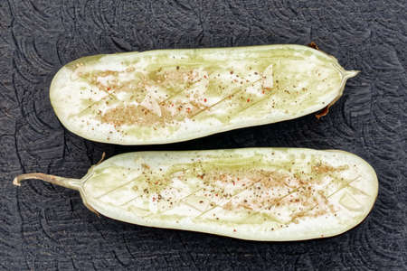 Eggplant prepared for grilling - seasoned with spices, garlic and olive oil, tonedの写真素材