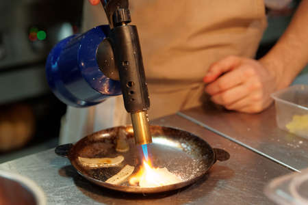 Chef is cooking onion slices with gas burnerの写真素材