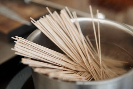 Buckwheat noodles being cooked on induction stoveの写真素材