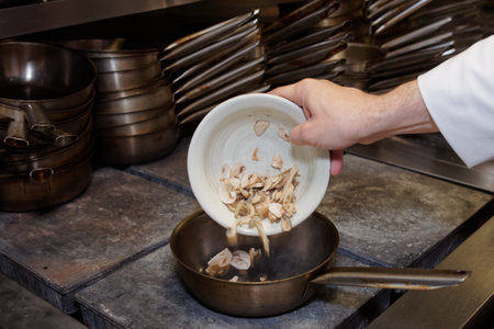 Chef is frying mushrooms at commercial kitchen